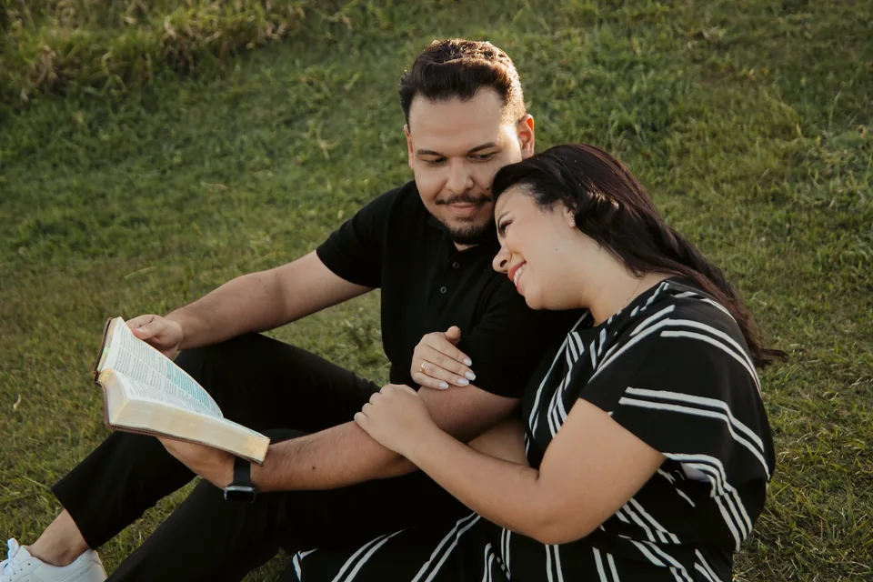 Romeu e Bianca deitados no gramado com um livro