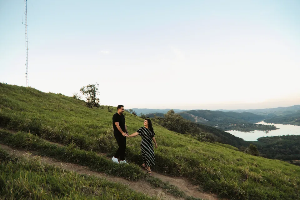 Bianca e Romeu andando de mãos dadas com a paisagem ao fundo