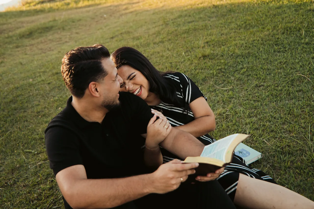 Bianca e Romeu sentados juntos, sorrindo no campo